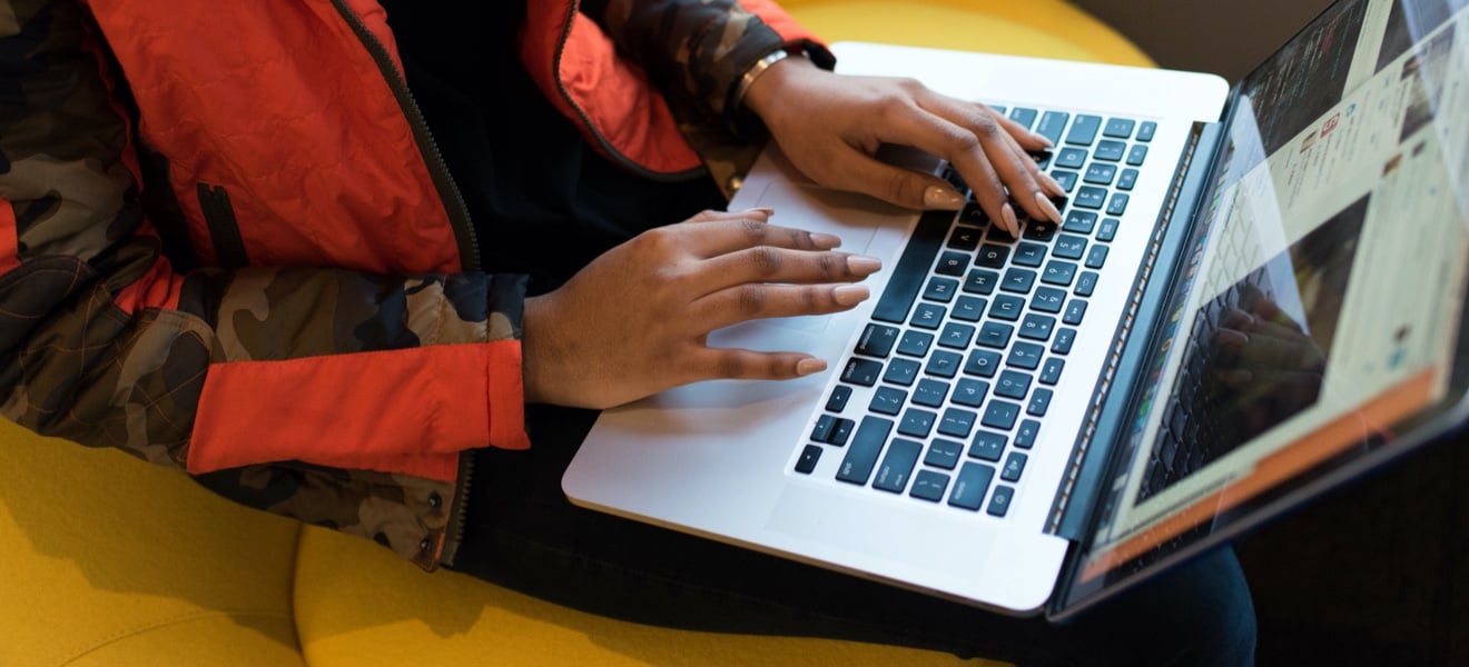 Closeup of hands on a laptop keyboard.