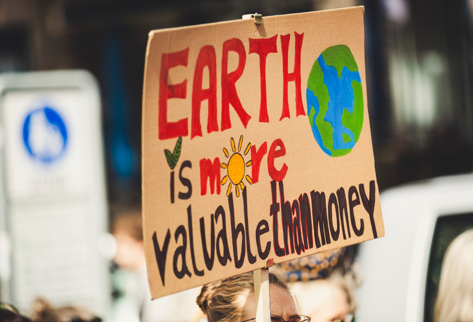 A cardboard sign from a protest reading 'Earth is more valuable than money'.